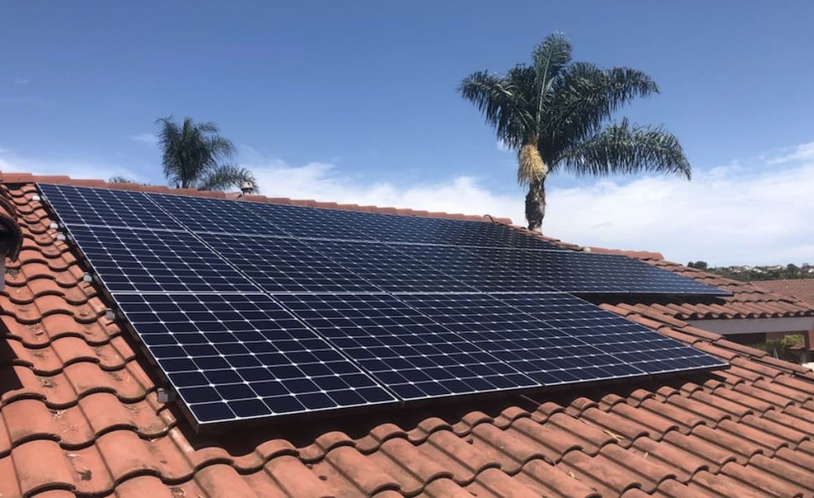 Solar panels installed on a Southern California tile roof with palm trees against a blue sky